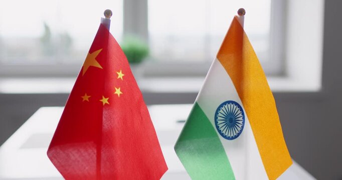 Flags show diplomacy, negotiation, bilateral dialogue, relations. China and India desk flags on a table suggest talks on trade, borders and security. Bilateral talks, policy focus stated.