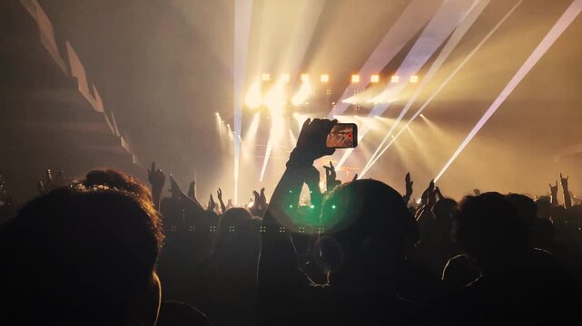 Silhouette crowd raising hands at a live rock concert with dramatic stage lighting, celebrating the excitement of live music.