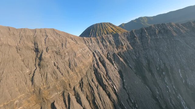 Cinematic FPV drone flight over Mount Bromo crater toward Mount Batok inside Tengger caldera in East Java, Indonesia. Dramatic volcanic landscape at sunrise in Southeast Asia.