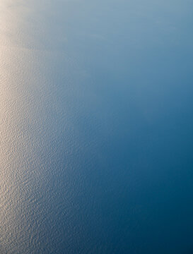 Looking down on vast blue ocean from airplane window.