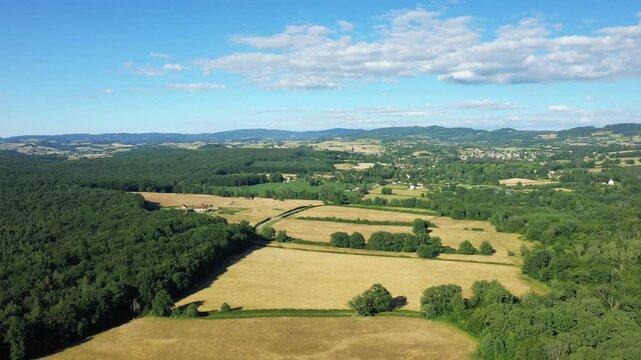 Scenic aerial landscape of fields and forests near Saint Honore les Bains in rural France, under a blue sky with scattered clouds.