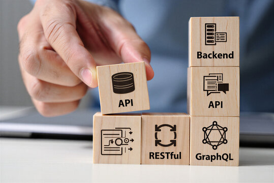 Developer stacking wooden blocks with API backend restful and graphql symbols representing software development process