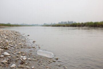 Discarded Plastic Bottle on Riverbank, Environmental Damage