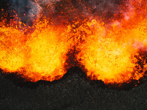 Aerial view of fiery rivers of molten lava carve through the stark, blackened earth, a dramatic clash of elemental forces in Iceland, Grindavik, Grindavikurbaer, Iceland.