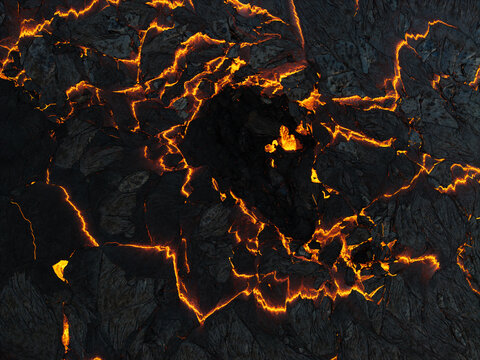 Aerial view of fiery lava flows seething through the dark, fractured earth, a stark contrast of molten orange against the cool, solid ground, Grindavik, Iceland.