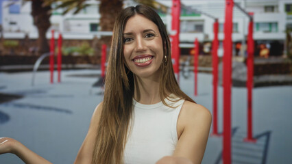 Fototapeta premium Woman with open hands smiling in gym surrounded by workout bars and outdoor sports equipment; happiness.
