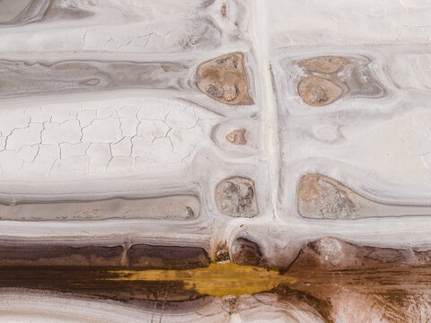 Aerial view of cracked earth and mineral deposits create an abstract landscape of contrasting hues, reminiscent of an arid canvas, Old Chandler, Western Australia, Australia.
