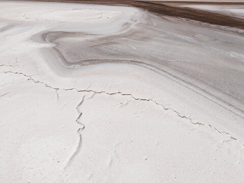 Aerial view of cracked earth forming intricate patterns of white and brown, creating a stark contrast in the landscape, Old Chandler Potash Mine Site, Western Australia, Australia.