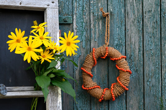 Yellow Jerusalem artichoke flowers and autumn wreath on rustic wall
