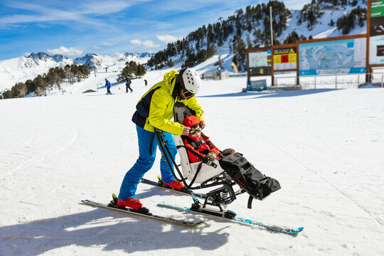 Ski instructor assists child with cerebral palsy adaptive skiing outdoors