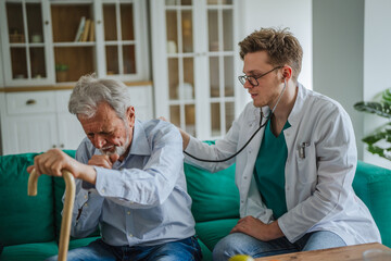 Fototapeta premium Doctor checking senior man's back with stethoscope during home visit