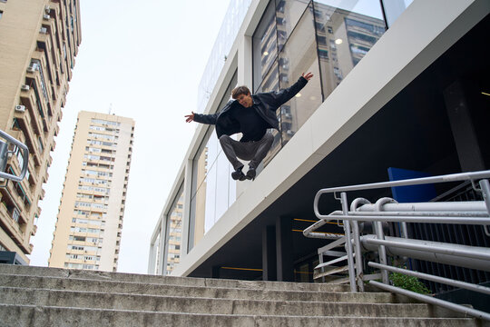 Man jumps dynamically over city stairs with urban energy outdoors