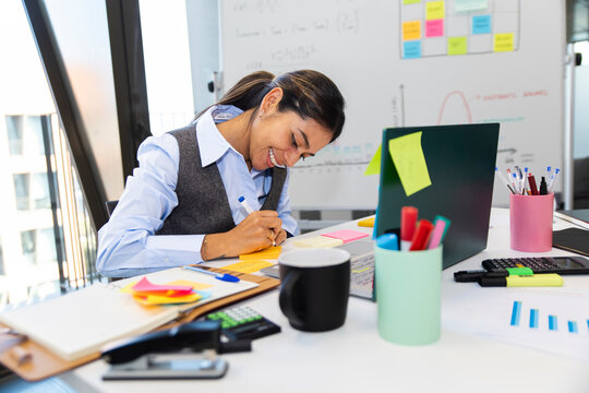 Manager writing colorful sticky notes at organized office desk
