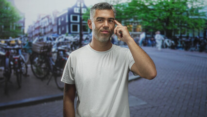 Fototapeta premium Man touching temple with finger beside crowded bicycle parking on a busy city street; thoughtful reflection.