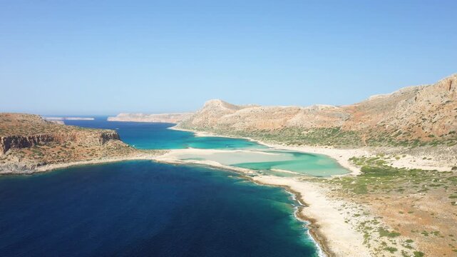 Stunning aerial view of the turquoise Balos Beach lagoon surrounded by rocky hills and clear blue sea in Crete, Greece. Bright summer sky and natural coastal landscape.