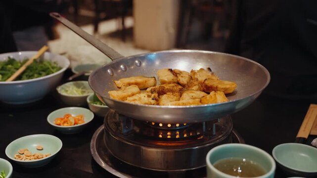 Chefs prepare traditional cha ca fish with turmeric and fresh herbs at Cha Ca Thang Long restaurant in Hanoi, Vietnam, showcasing a classic northern Vietnamese culinary experience.