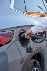 Hand plugging electric vehicle into charging station