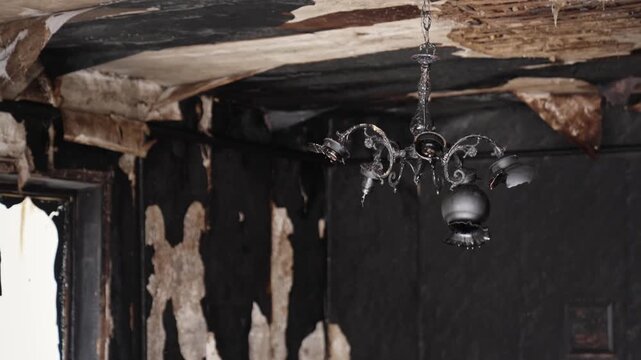 Burnt chandelier on the ceiling of a burnt house after a major fire. Remains of a destroyed wooden building destroyed by fire, accident
