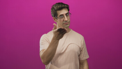 Obraz premium Man with glasses and wedding ring forms heart with hands in a pink studio, smiling and leaning forward in mid motion offering the gesture; warm affection.