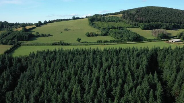 Aerial view of lush green fields and dense forests in the Morvan countryside, France, under a clear blue sky. Scenic rural landscape with gentle hills and natural beauty.