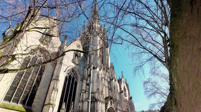 Reveal shot of Saint Maurice Church in Lille, showcasing Gothic facade and historic stone detail under clear blue sky.
