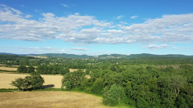 Scenic view of rolling fields and forests under a blue sky in the Morvan countryside, France. Peaceful rural landscape with distant hills and scattered trees.