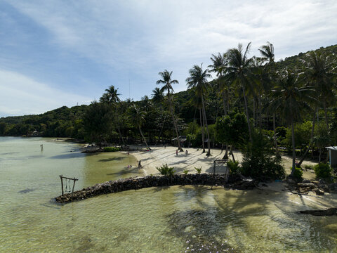 Aerial view of Bobby Beach with its dazzling turquoise waters meeting the soft, pale sands beneath the swaying silhouettes of palm trees, Karimunjawa, Central Java, Indonesia.