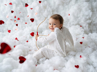 Baby angel sitting among fluffy clouds and heart-shaped decorations  