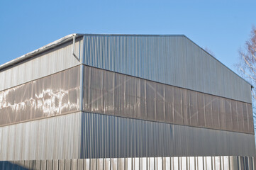 Fototapeta premium A close-up of a gray metal fence with a metal hangar and blue sky in the background
