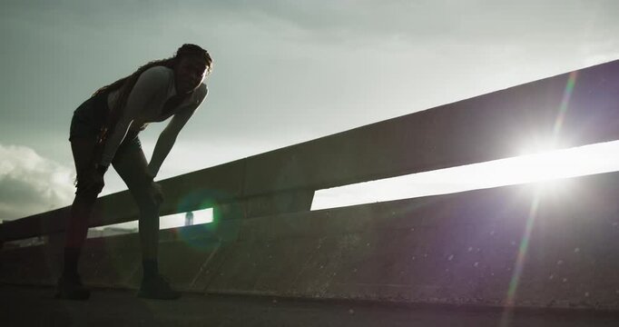 Tired, black woman and rest for fitness in city with burnout, breathing and exercise break. Below, exhausted and person with fatigue, intense training or recovery from sports workout at outdoor flare