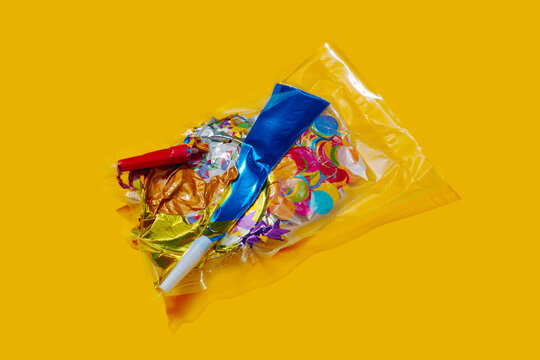 Vacuum sealed party supplies with confetti and balloons on yellow background