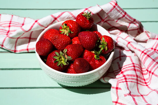 Fresh strawberries in a bowl on garden table outdoors