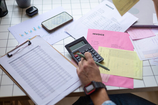 Hand using calculator for business accounting and invoice paperwork
