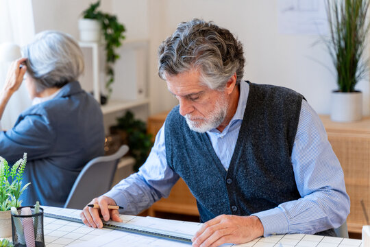 Businessman focusing on architectural plans at office desk