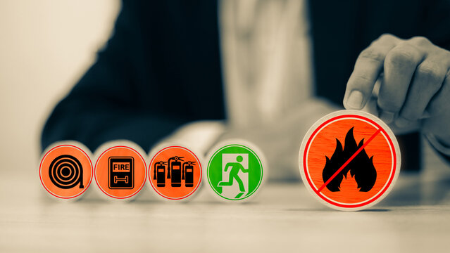 Hand chooses door exit sing on wooden toy stack for fire escape to prevent with fire extinguisher and emergency prevention protection symbol for safety first and rescue and training concepts.