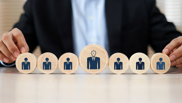 Hand chooses person HR human resources icons on wooden toy for leader or group teamwork people officer or business planning or team player and personnel management job performance.