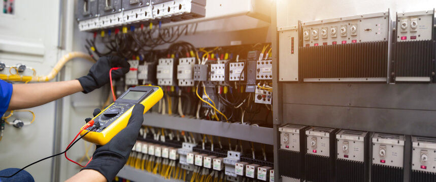 Electrical service technician use electricity measuring tools equipment checking electric current circuit breaker terminal panel and cable wiring main power distribution board for maintenance system.
