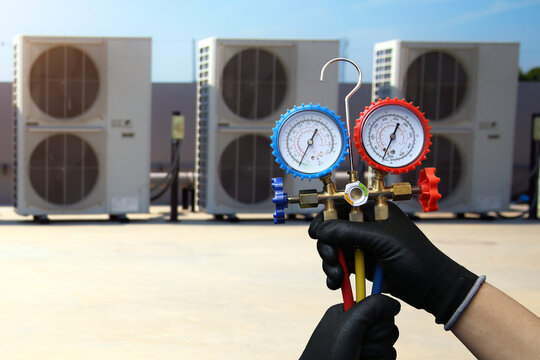 Air conditioning electrical technician service using measuring manifold gauge checking HVAC condition system and refrigerant filling air conditioner after cleaning and maintenance compressor units.