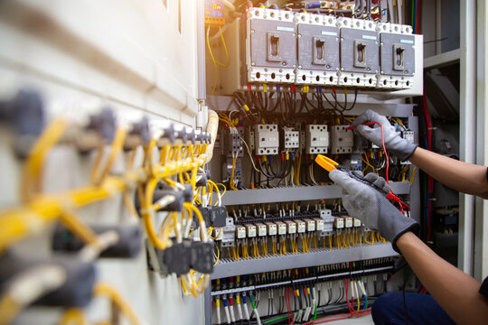 Electrical service technician use electricity measuring tools equipment checking electric current circuit breaker terminal panel and cable wiring main power distribution board for maintenance system.