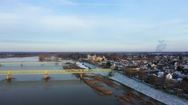 Aerial view of Sully sur Loire with its historic castle, snow dusted rooftops, and bridges crossing the Loire River on a winter day.