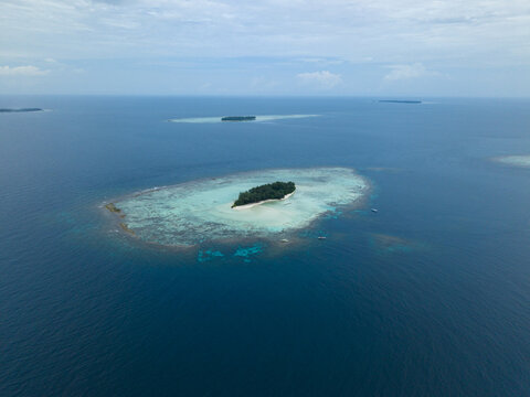 Aerial view of a small island surrounded by turquoise shallows contrasting with the deep blue ocean, Cemara Kecil Island, Karimunjawa, Central Java, Indonesia.