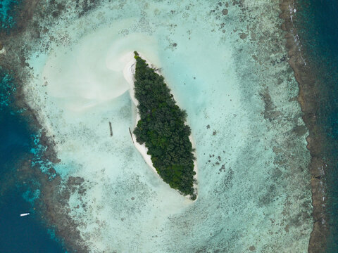 Aerial view of a vibrant island surrounded by turquoise waters and coral reefs, a tropical haven, Karimunjawa, Central Java, Indonesia.