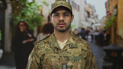 Man in camouflage military uniform stands upright and looks ahead with steady gaze on crowded street  service honor commitment duty. © Krakenimages.com