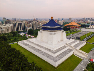 Aerial angular rear view of the Chiang Kai-Shek Memorial Hall in Taipei, Taiwan, with the surrounding park and the dense city skyline of Taipei visible in the background.


