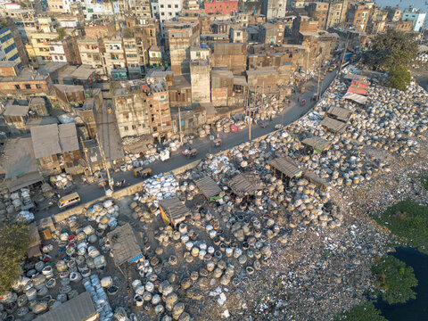 Aerial view of mountains of plastic waste stretch alongside the Buriganga River under a hazy sky, plastic waste recycling zone, Dhaka, Dhaka Division, Bangladesh.
