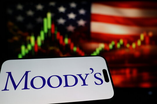 Kiel, Germany - 03-03-2026: US credit rating agency Moody's Corporation logo on smartphone against US flag and rising stock market candlestick chart concept