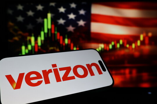 Kiel, Germany - 03-03-2026: US telecommunications company Verizon Communications Inc. logo on smartphone against US flag and rising stock market candlestick chart concept