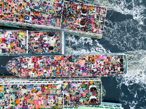 Aerial view of ferries packed with colorful crowds create a vibrant tapestry on the dark waters, Dhaka, Dhaka Division, Bangladesh.