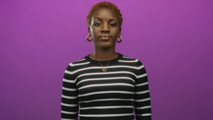 Woman in black and white striped top wearing gold hoop earrings and heart necklace with open mouth in studio  surprise. © Krakenimages.com