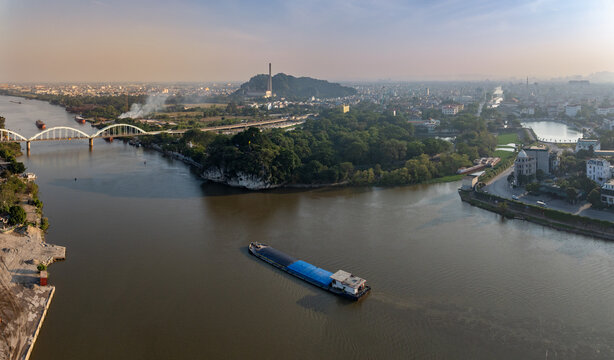 Aerial view of a cargo barge on  River Day, passing Non Nuoc Railway Bridge in Ninh Binh, Vietnam. Industrial city with ongoing development.